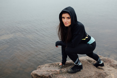 Young fit woman stand on rocks and rest after a hard workout. Motivation, sport and fitness lifestyle concept. Whater background.の写真素材