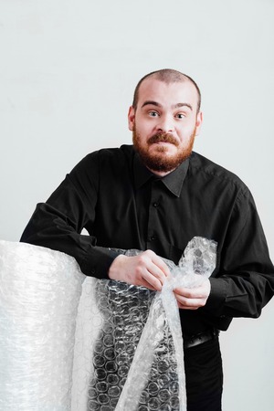 Portrait of a red-bearded, balding male brutal. White isolated background. A man in a black shirt pants.  Business man funny relax with plastic wrap.の写真素材