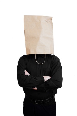 Portrait of a red-bearded, balding male brutal. White isolated background. Black shirt and pants. Paper bag over head. Dissatisfied with the situation  with arms foldedの写真素材