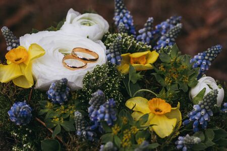 Beautiful wedding bouquet of different white, blue, green flowers, bunch close up with rings.の写真素材