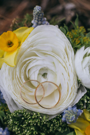 Beautiful wedding bouquet of different white, blue, green flowers, bunch close up with rings.の写真素材