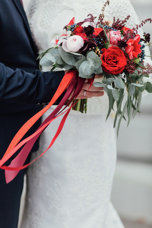 Bride and groom holding wedding bouquet with tape together, outdの写真素材