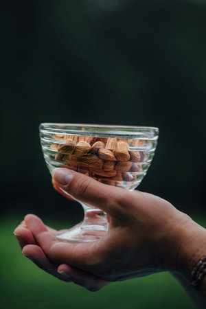 Close Up Of Woman Holding glass bowl with Almonds nuts.の写真素材