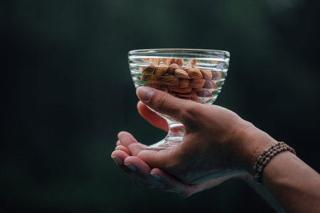 Close Up Of Woman Holding glass bowl with Almonds nuts.の写真素材