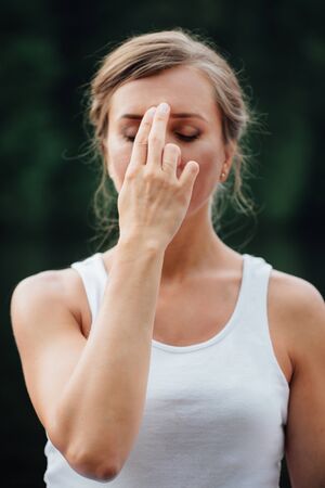 Young Woman Doing Yoga Meditation Exercises, symbolic hand gestures mudra. on the background of forest and riverの写真素材