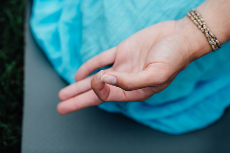 Woman meditating in lotus position closeup. Hands close-up mudra. Sitting on rug the lawn of green grass backgroundの写真素材