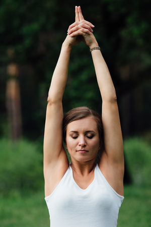 pregnant yoga in the lotus position on the forest background. in the park the grass mat, outdoor, health woman.の写真素材