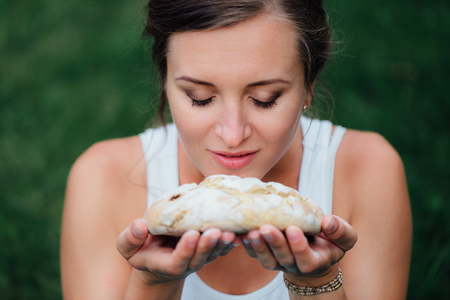 pregnant yoga prenatal maternity with  freshly baked homemade bread in hands in park on the grass.の写真素材