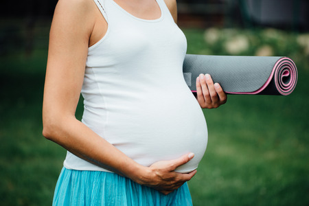 close-up pregnant yoga woman with mat portrait in park on the grass, breathing, stretching, statics. outdoor, forest.の写真素材