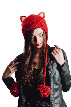 Pretty young woman wearing a hand knitted red hat on white background. Isolated. Beautiful girl in with Ear flap.の写真素材