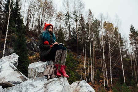 artist girl painting sitting on the rocks at the cliff, notepad. Wonderful fall viewの写真素材