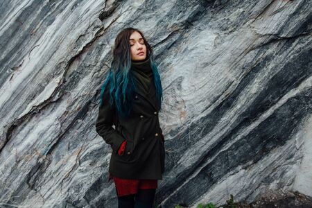 Portrait of a beautiful hipster girl on the background  the rocky cliffs. Dyed hair, blue, long.の写真素材