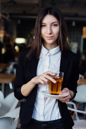 young cute brunette girl business in the interior hipster cafes holding a glass of tea.の写真素材
