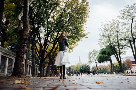 Beautiful girl walking on the cobblestone square. ancient area autumnの写真素材