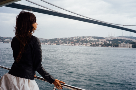 Girl tourist enjoying the view of the city from a boat. Cruise, tour, tourism. Background to the bridgeの写真素材