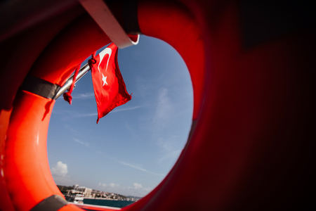 Flag of Turkey and lifebuoy on back of a boat in Bosphorus strait, Istanbul, Turkeyの写真素材