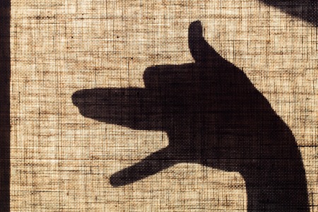The shadow of the hand and fingers in the form of a dog shaped mark on flax canvas.の写真素材