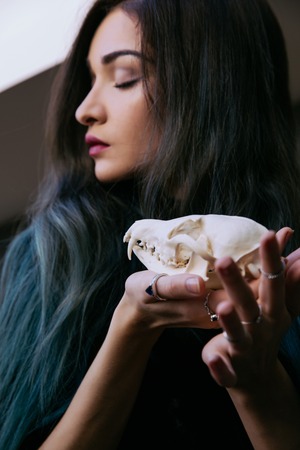 Portrait of a young girl holding a mysterious skull in the hands of a fox. Painted long hair.の写真素材