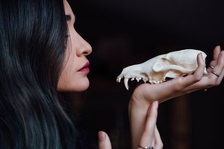 Portrait of a young girl holding a mysterious skull in the hands of a fox. Painted long hair.の写真素材