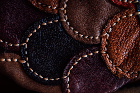 A fragment of a leather bag and a purse made of multi-colored pieces. White leather stitching.の写真素材
