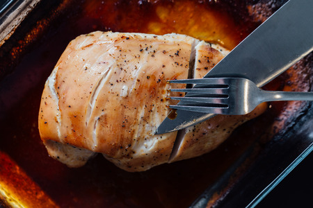 Breast of turkey with spices, rosemary in soy sauce. There is a knife and fork, the first cut.の写真素材