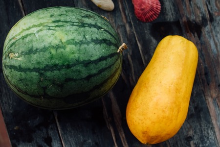 Watermelon and papaya whole lie on a wooden table. Fresh, juicy, delicious tropical fruits of Thailand.の写真素材