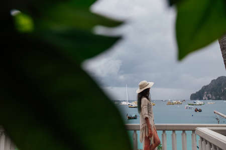 The girl in the hat is enjoying the view from the broadwalk at the sea.の写真素材
