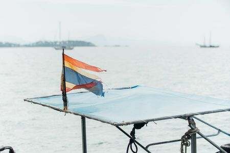 Old Thai flag on blue sea sky. Damaged Faded.の写真素材
