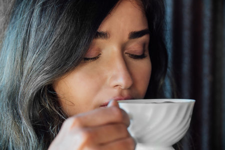 Portrait of a girl drinking coffee in a vintage cafe on the terrace in Asia. Sniffs, drinks.