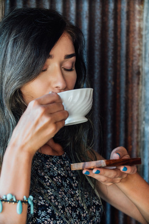 Portrait of a girl drinking coffee in a vintage cafe on the terrace in Asia. Sniffs, drinks.の写真素材