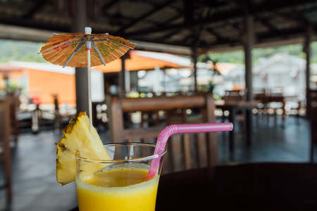 Refreshing pineapple cocktail glass with slices of pineapple, pink juice straws and decorationの写真素材