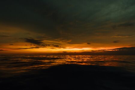 Gloomy sunset in evening sea. Beautiful sunset in cloudy sky on oceanの写真素材