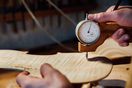 Master artisan luthier working on the creation of a violin. painstaking detailed work on wood.の写真素材