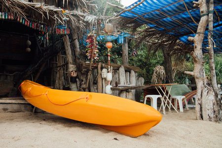 Yellow kayak on beach under a thatched roofの写真素材