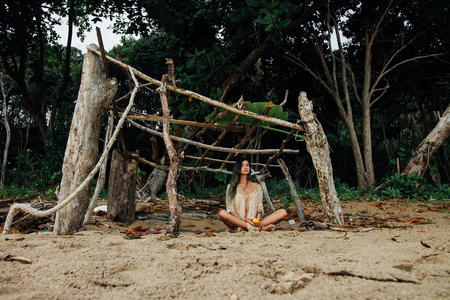 Young beautiful woman sits in lotus position on on background tropical forestの写真素材