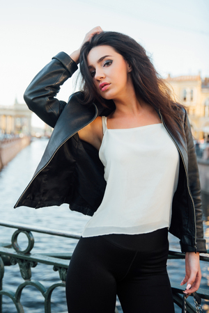 Portrait of a beautiful sexy brunette posing on a bridge on a river background.の写真素材