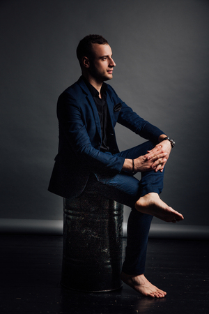 Portrait handsome fashionable man in a black shirt sits on a chair in a photo studio loft.の写真素材