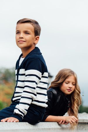 Two cute kids are sitting on the railing. Marble-stone fountain.の写真素材