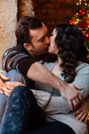 Couple of lovers hugs sitting on the windowsill in the Christmas loft studio. guy is hugging the girl.の写真素材