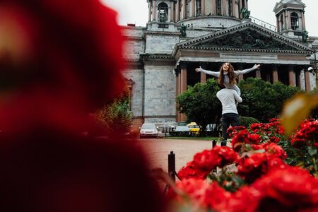 loving couple hugs against a background of red flowers and vintage architecture.の写真素材