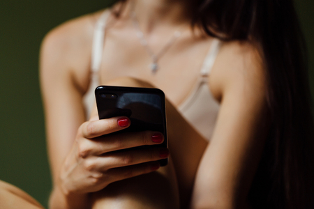 Beautiful modern ballet dancer with perfect body holds a cell phone in his hand. Type message.の写真素材