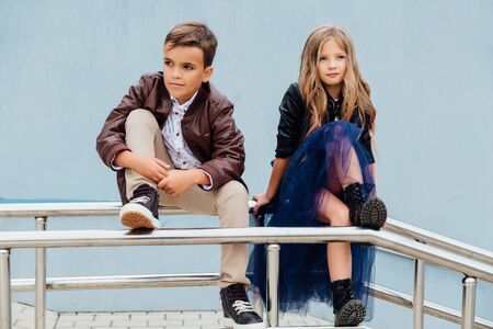 Children, a boy and a girl are sitting on the railing in the park friends. Concept of friendship.の写真素材