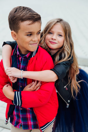 girlfriend hugs a guy from behind in the street in the city. Two children together embrace.の写真素材