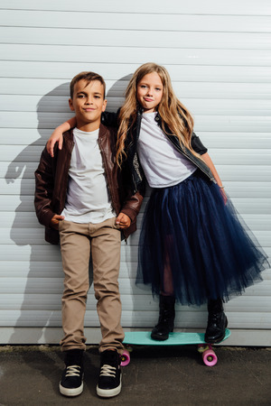Portrait of two teenage school children on a garage door background in a city park street.の写真素材