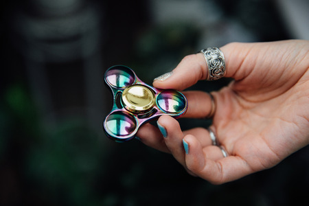 Girls hand with fidget spinner. Holds a shiny metallic hand spinner. Hippies and Bohemia.の写真素材