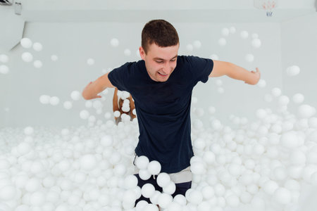 couple of loving friends have fun surrounded by white plastic balls in a dry swimming pool.の写真素材