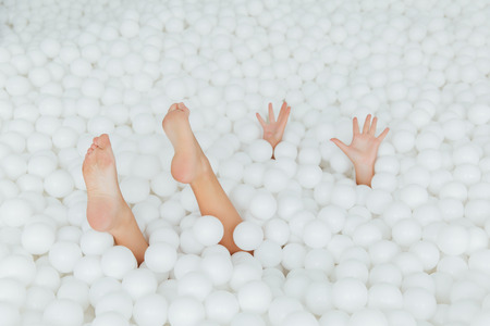 woman body parts stick out white plastic balls in the dry pool. Copy splace.の写真素材