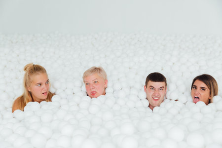 Happy Friendly family surrounded by white plastic balls in the dry pool.の写真素材