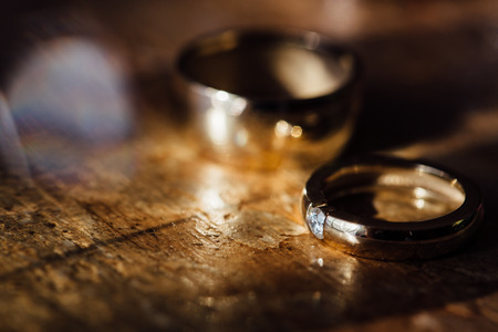 Two beautiful golden wedding rings and earrings on a wooden background.の写真素材