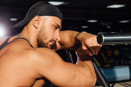 Big strong man fitness model resting in the gym. leaned against the simulator sport equipment.